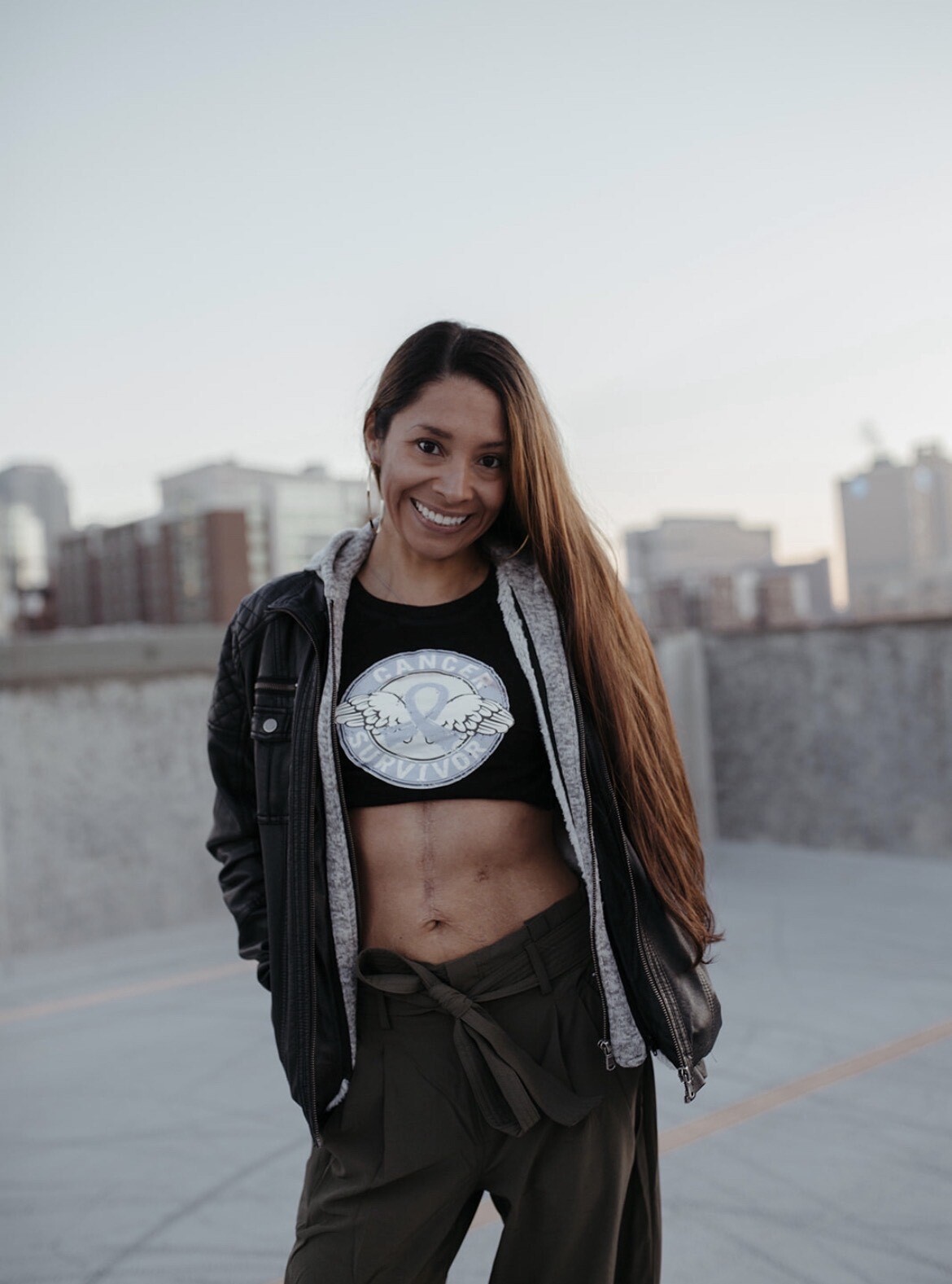 Photograph of Priscilla Brittine smiling, wearing a black shirt and open hoodie.